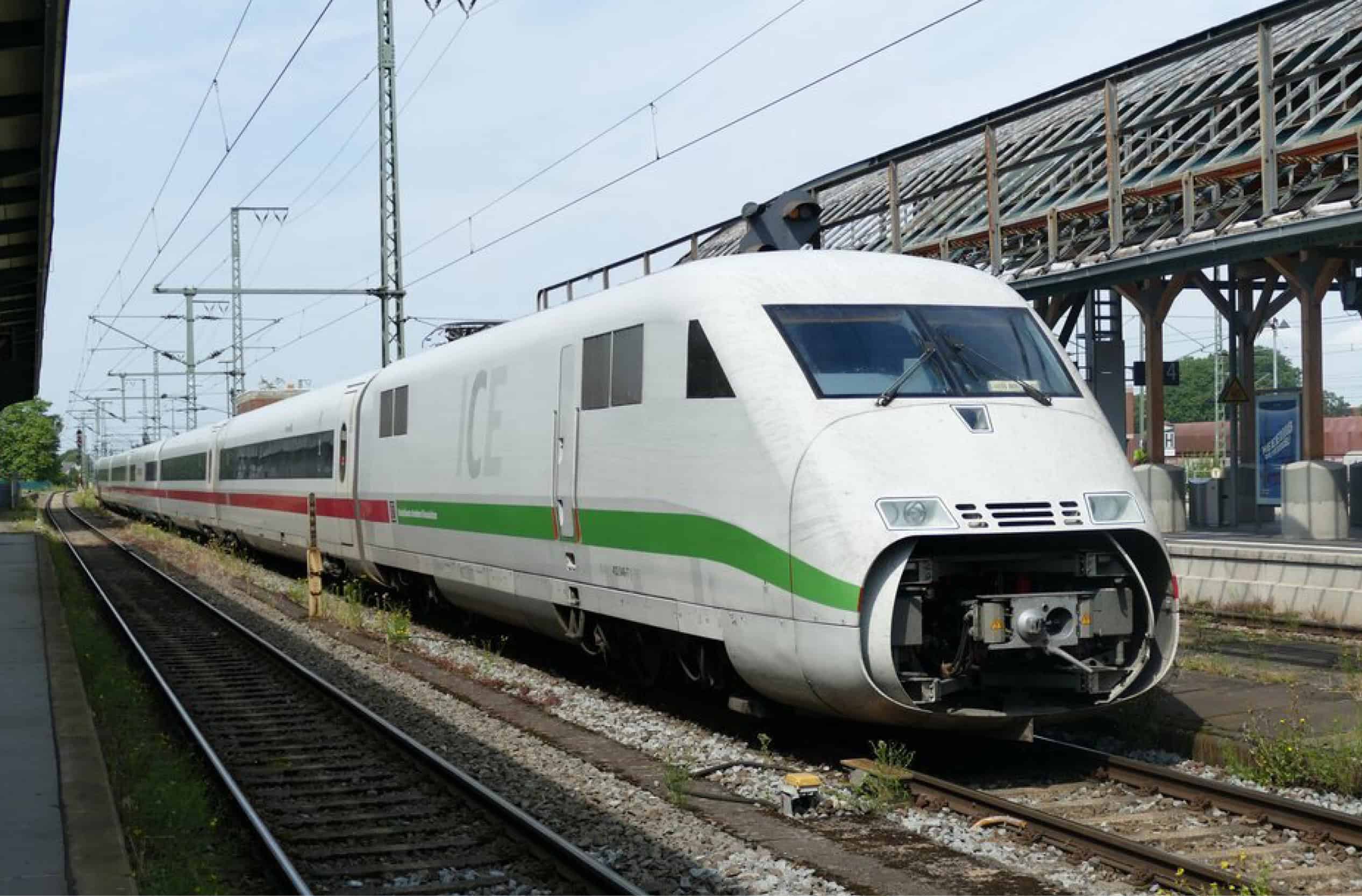 Ein ICE mit grünem Streifen steht in einem Bahnhof.